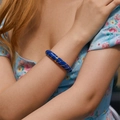 Dettaglio del bracciale smaltato blu con strisce dorate indossato da una modella - Blu scuro
