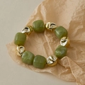 Gros plan de perles en résine vert olive et métal doré texturé sur papier kraft - Marbre Vert Olive (AB0050-12)