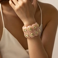 Vue macro d'un large bracelet en résine marbrée rose avec clous dorés pour femmes - AB0049-2