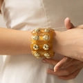 Dettaglio di bracciale rigido in acrilico ambra con inserti a disco in metallo dorato - Ambra Traslucido (AB0049-3)