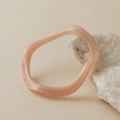 Detail of pink marble acrylic wavy bracelet resting on a white mineral stone - Light Pink Marble Wave Style (AB0026-1)