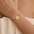 Elegant 18K gold plated stainless steel bracelet with a sunburst round charm on model - Stainless Steel / Sunburst Pattern (SB0006)