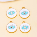 Close-up of four golden Evil Eye enamel charms for DIY jewelry making and necklace crafts - White