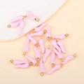 Flat lay view of pink chili pepper pendants with golden rings for DIY jewelry making - Pink