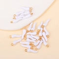 Macro detail of white enamel cornicello chili charms with gold loops for DIY jewelry making - White
