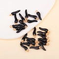 Macro detail of black chili pepper charms with gold rings for DIY jewelry making - Black