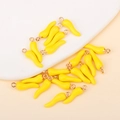 Macro shot of bright yellow chili pepper enamel charms with gold rings for DIY jewelry - Yellow