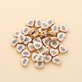 Close-up of heart-shaped evil eye spacer beads with gold trim and white enamel for DIY jewelry - Heart Shape (px0942-18)
