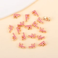Détail macro de la perle lettre F en alliage doré avec émail rose pour bijoux faits main - F (px0918)