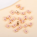 Détail macro de breloques lettre R dorées avec émail rose pour la création de bijoux - R (px0918)
