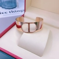 Vista macro del bracciale rigido dorato con scritte CD traforate in una confezione regalo - Fila a spirale oro rosa