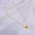 Macro detail of golden heart pendant necklace on soft white fabric background - Golden Necklace