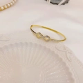 Macro shot of 18K gold plated infinity bracelet with micro-pave white zircons on ceramic tray - Single Bangle Gold