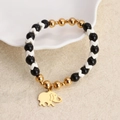 Handgemaakte kralenarmband met zwarte harskralen en een gouden olifanthangertje - Zwart en Witte Kartel Kralen Olifant Hanger Stijl (08)