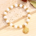 Pulsera oceánica con perlas blancas, cuentas doradas y colgante de concha sobre mármol - Estilo Concha (04)