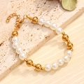 Elegant beaded bracelet with white pearls and gold metal beads on a stone surface - Bracelet