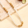 Elegant necklace with white round pearls and polished golden beads on a natural stone base - Necklace