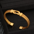 Brazalete abierto de acero inoxidable chapado en oro de 18k con diseño de nudo central - Dorado