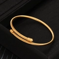 Elegante brazalete de alambre trenzado dorado con puntas esféricas sobre fondo negro - Dorado