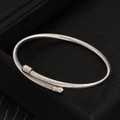 Brazalete rígido de acero inoxidable plateado con diseño trenzado y puntas de bola - Plateado