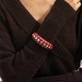 Macro shot of punk style resin bangle with silver studs worn over a brown sweater - Red (3049)
