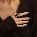Close-up of tortoise resin ring with silver studs worn over a brown knit sweater - Rivet Ring / Amber (0978)
