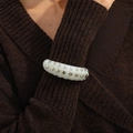 Close-up of white resin cuff bracelet with silver studs on a brown knitted sweater sleeve - White (3049)