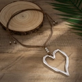 Detail van zilveren hartvormige hanger met hamerslag op bruine geweven waskoord - Trend Grote Hart Halsketting