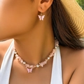 Dettaglio della collana e degli orecchini con farfalla rosa indossati per l'estate - Set Di Collana E Orecchini / Oro + Rosa