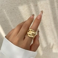 Gros plan d'une large bague dorée à couches torsadées avec finition mate sur la main - 03 Bague Dorée 0749
