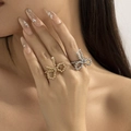 Detail of beaded metal bow rings in gold and silver finish on a female model hand - Gold + Silver