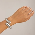Dettaglio di un bracciale a fascia rigida a goccia d'argento con finitura lucida - Stile a forma di goccia fluida / Oro 18K