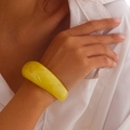 Close-up of a glossy yellow chunky acrylic bangle bracelet with smooth curved texture - Yellow (2473)
