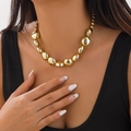 Gros plan d'un collier ras du cou à billes dorées porté par un mannequin pour un look rétro - Collier Or