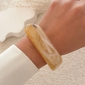 Close-up of translucent amber marble acrylic bangle worn on wrist over plush background - Light Coffee (2503)