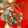 Detail of green and white clay bead hoop earrings hanging on branch with bokeh lights - Green White Stripe Style (3423K5)