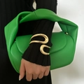 Close-up of a minimalist irregular gold bangle paired with a vibrant green handbag - Spiral Open Bracelet (2546) / Gold
