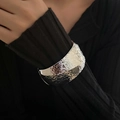 Detail of wide hammered texture open cuff bracelet in silver finish on black sleeve - Wide Hammered Style (2548) / Silver