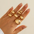Polished gold multi-piece ring set with irregular pebble design on model's hand - 02 Light Gold Ring Set (5524)