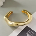 Macro detail of chunky gold wave bangle with high-gloss metallic finish on grey background - Irregular Wave (2267) / Light gold
