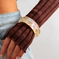 Detalle de un brazalete grueso de resina iridiscente con acabado perlado en una muñeca - 04 Amarillo 2656