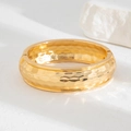 Golden wide hammered cuff bracelet with a polished finish and hinged spring closure - Gold