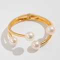 Detalle de brazalete dorado texturizado con perlas blancas y cierre de bisagra elástica - Brazalete Perla Oro