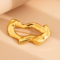 Detailed view of golden irregular wavy textured brooch with molten lava metal surface - Gold