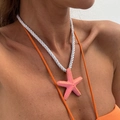 Primer plano de colgante de estrella de mar rosa con puntos dorados y cordón blanco - Collar Rosado (7105k4)