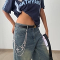 Dettaglio di catene incrociate d'argento a strati sui jeans per uno stile punk Y2K - Stile Gancio Croce Vintage (1679)