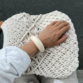 Close-up of a wide cream resin bangle on a woven bag with a minimalist retro style - Bangle / Off White