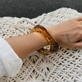 Detailed view of amber marble resin bracelet featuring translucent textures on the wrist - Amber (2945)