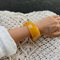 Dettaglio di un ampio bracciale in acrilico ambra con finitura in resina lucida - Giallo Zenzero