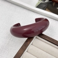 Close-up of a burgundy resin open bangle resting on a velvet jewelry display box - Cuff Bracelet / Red
